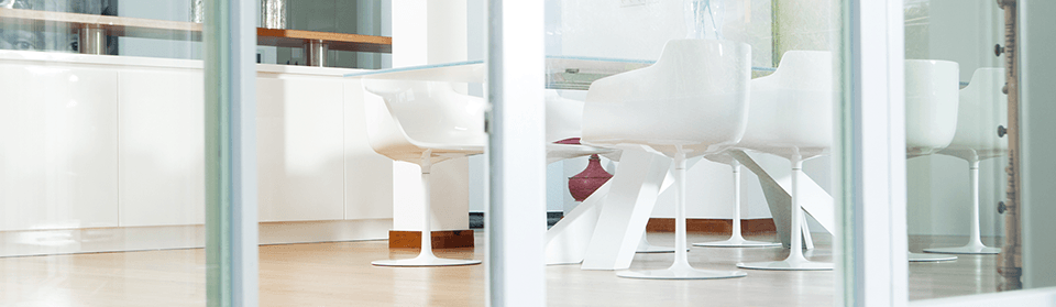 Einblick in ein Zimmer mit Glasstisch und weißen Stühlen