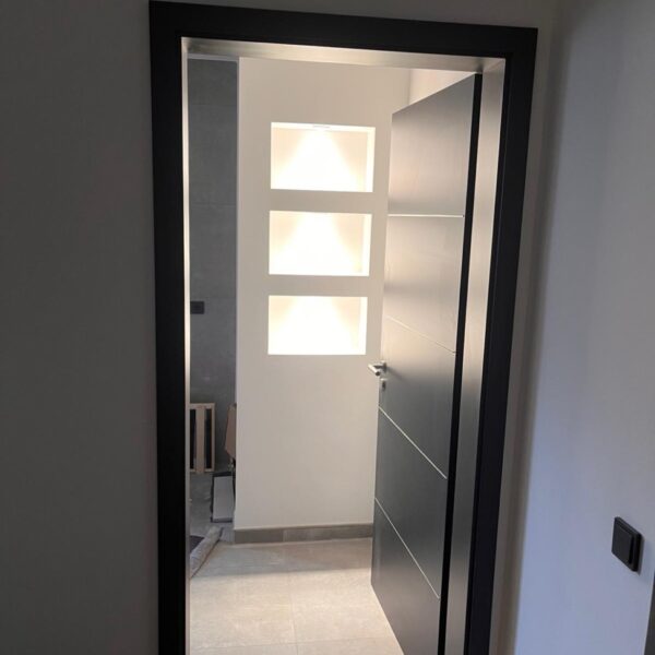 Moderne schwarze Innentür mit Blick auf beleuchtete Wandnische.